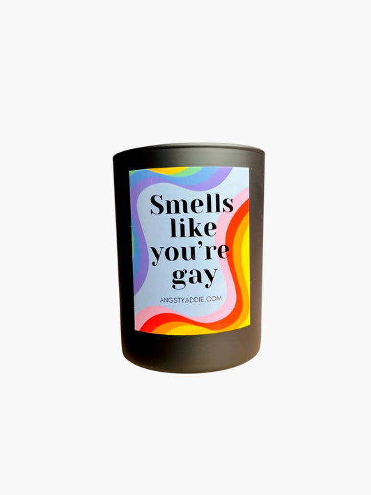 Candle with a colorful label reading 'Smells like you're gay' on a white background
