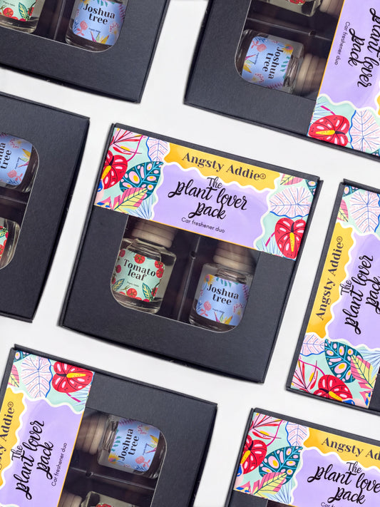 multiple identical black boxes with colorful labels, each containing a small glass jar with a plant-related label.