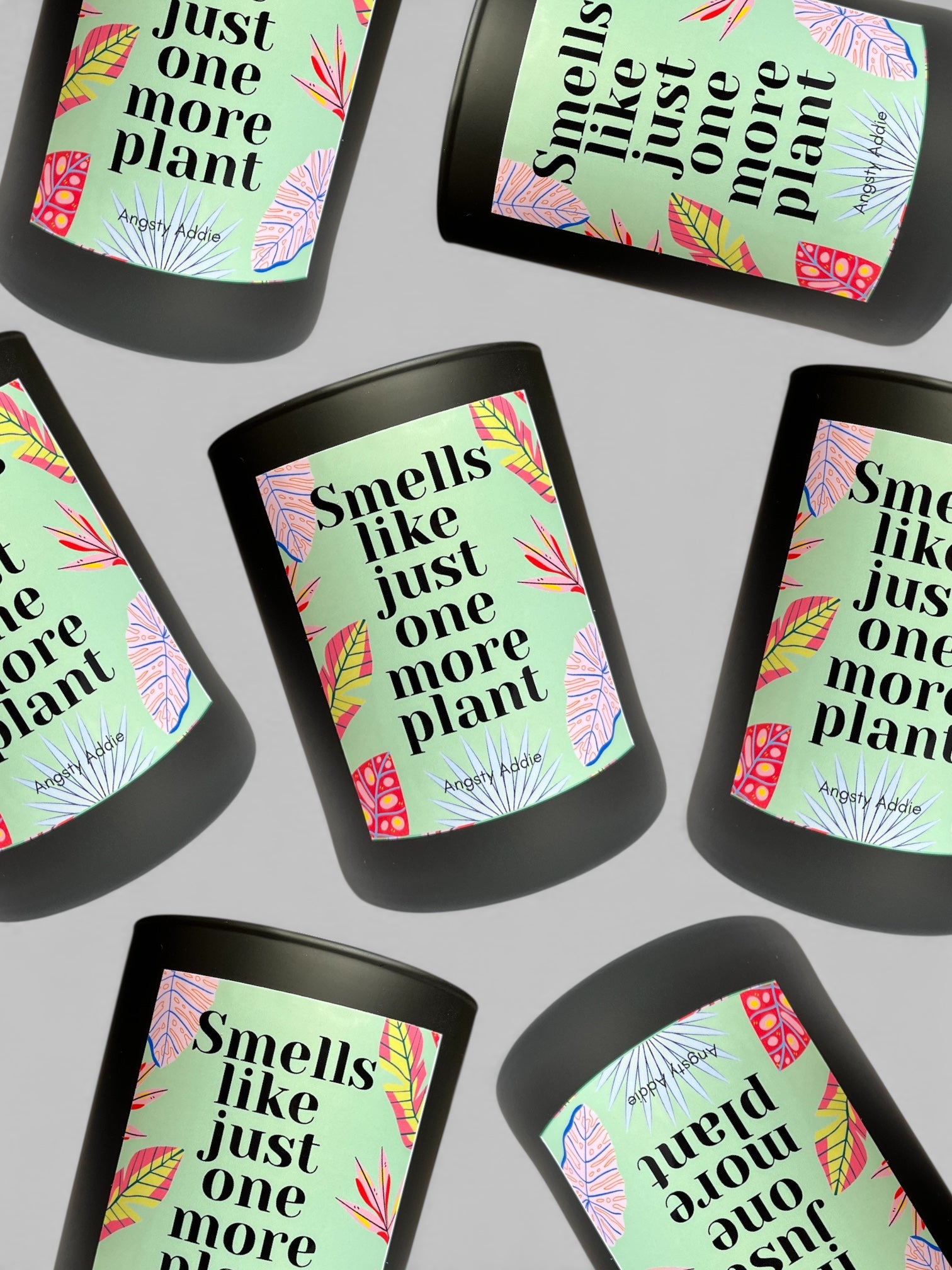 Multiple candles with 'Smells like just one more plant' text on a gray background